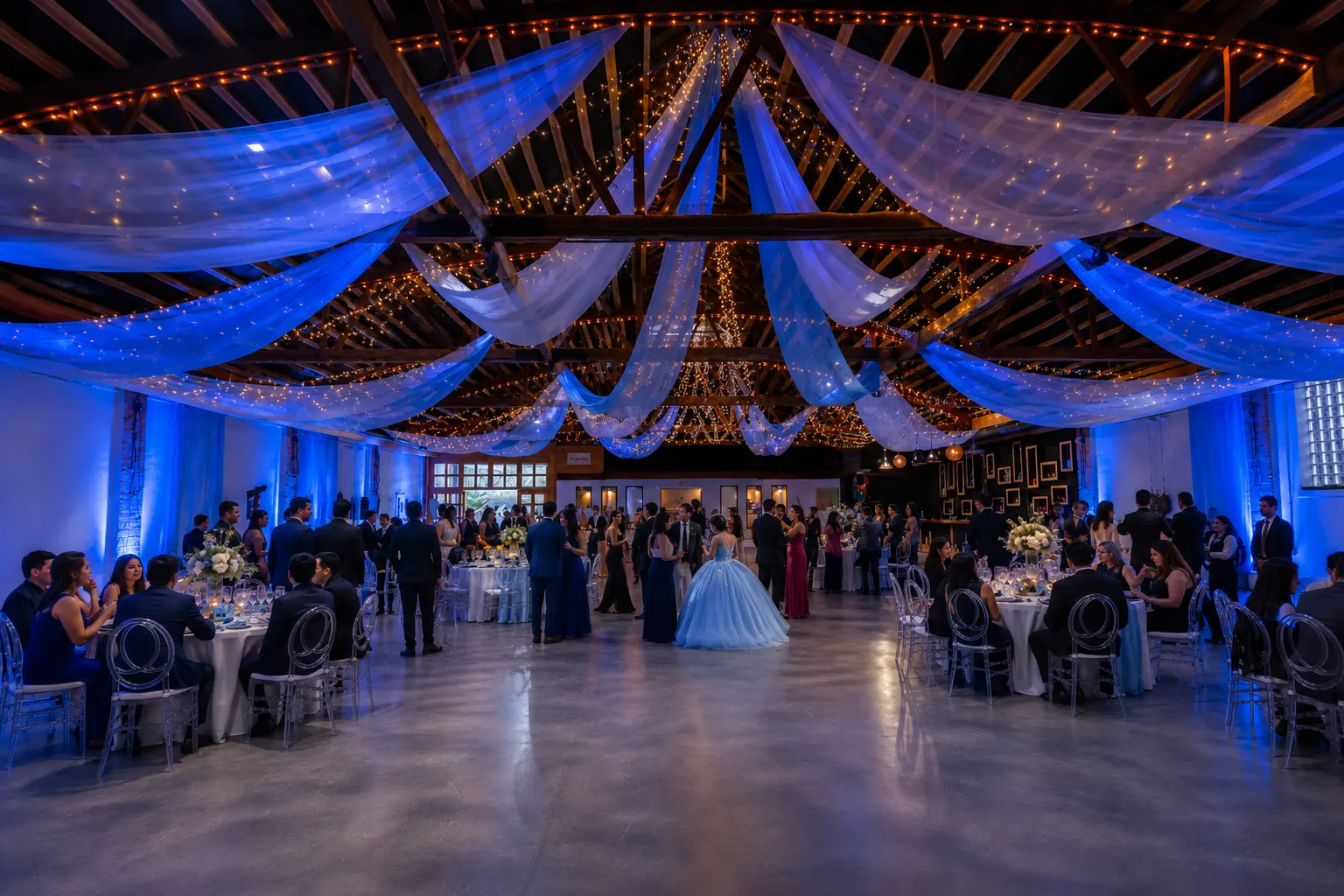 Guests celebrating beneath the draped, light-strung ceiling of the main room