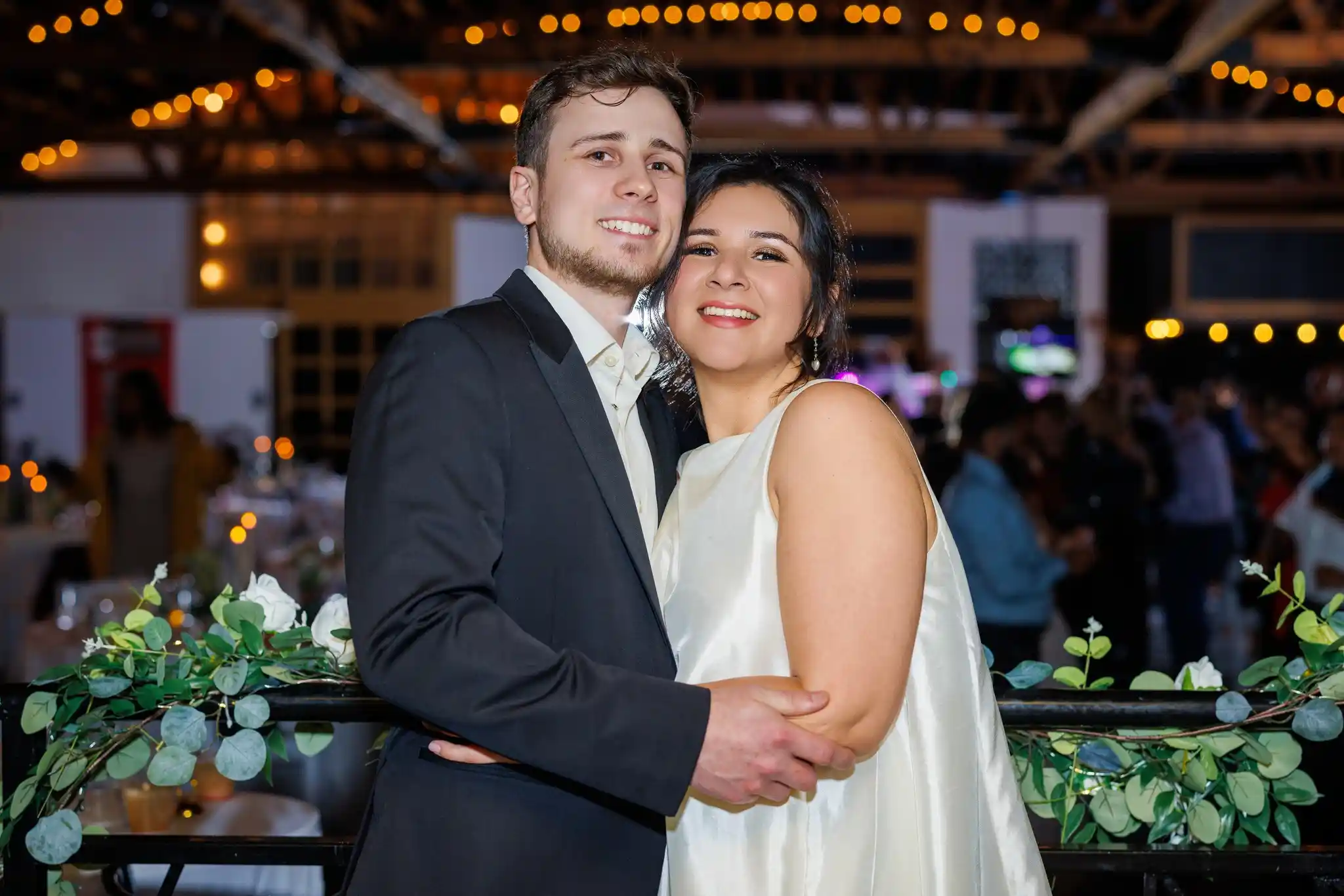 A newlywed couple sharing a quiet moment amid their reception beneath the warm string lights